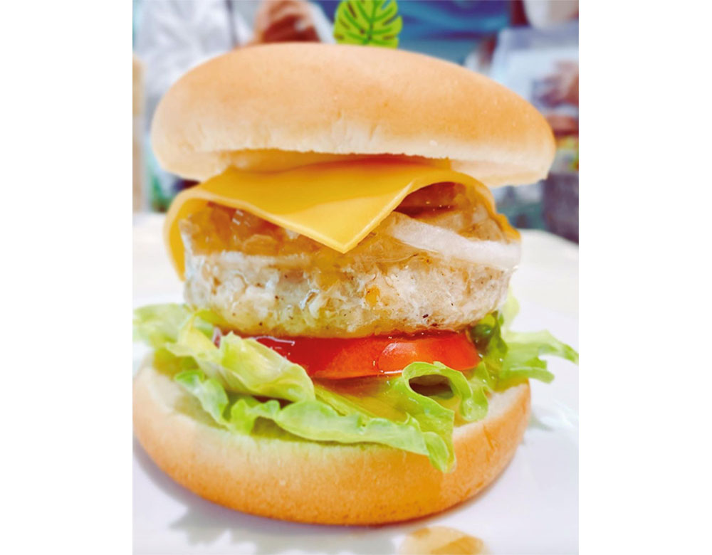 写真：鶏肉のパティとレタス、トマト、チーズを挟んだハンバーガー