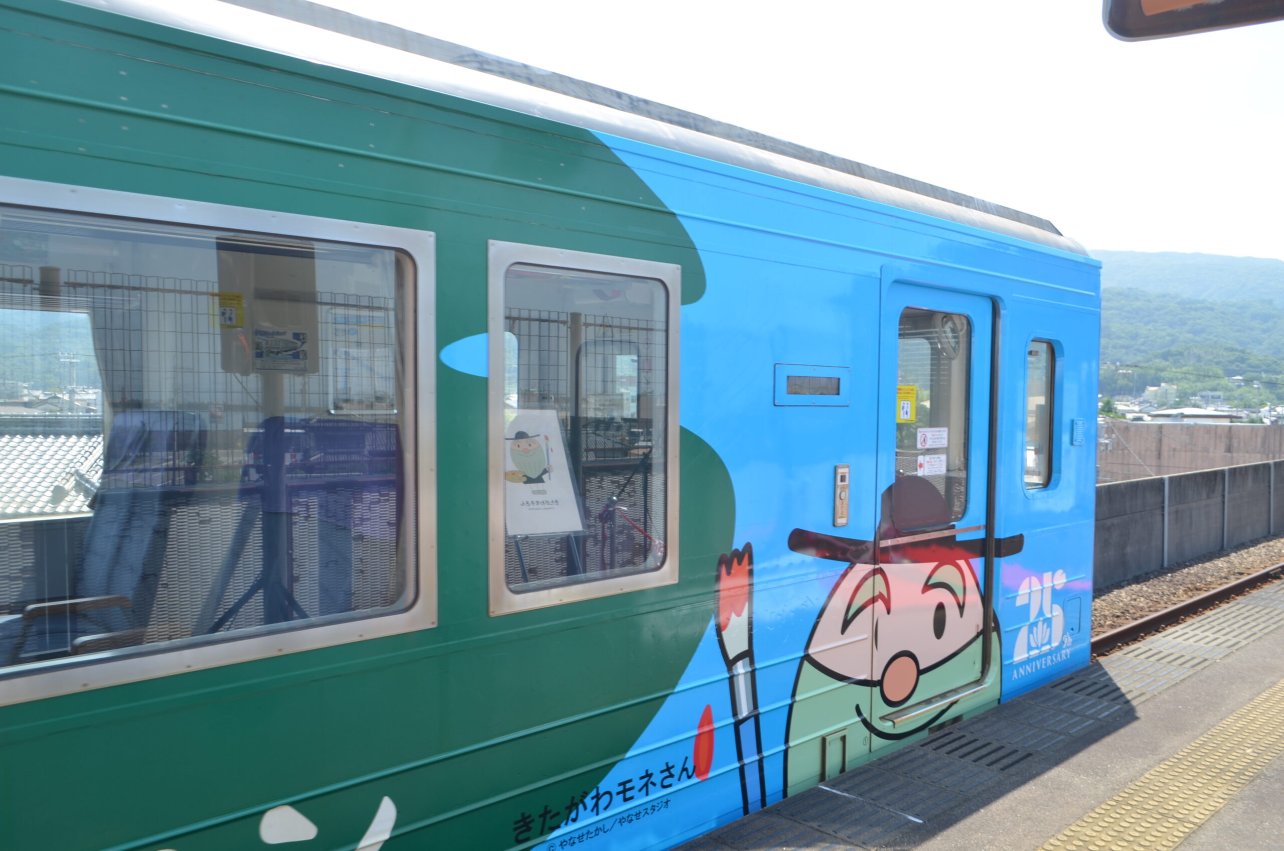 25周年記念のラッピング列車。水色の車体にきたがわモネさんが描かれている